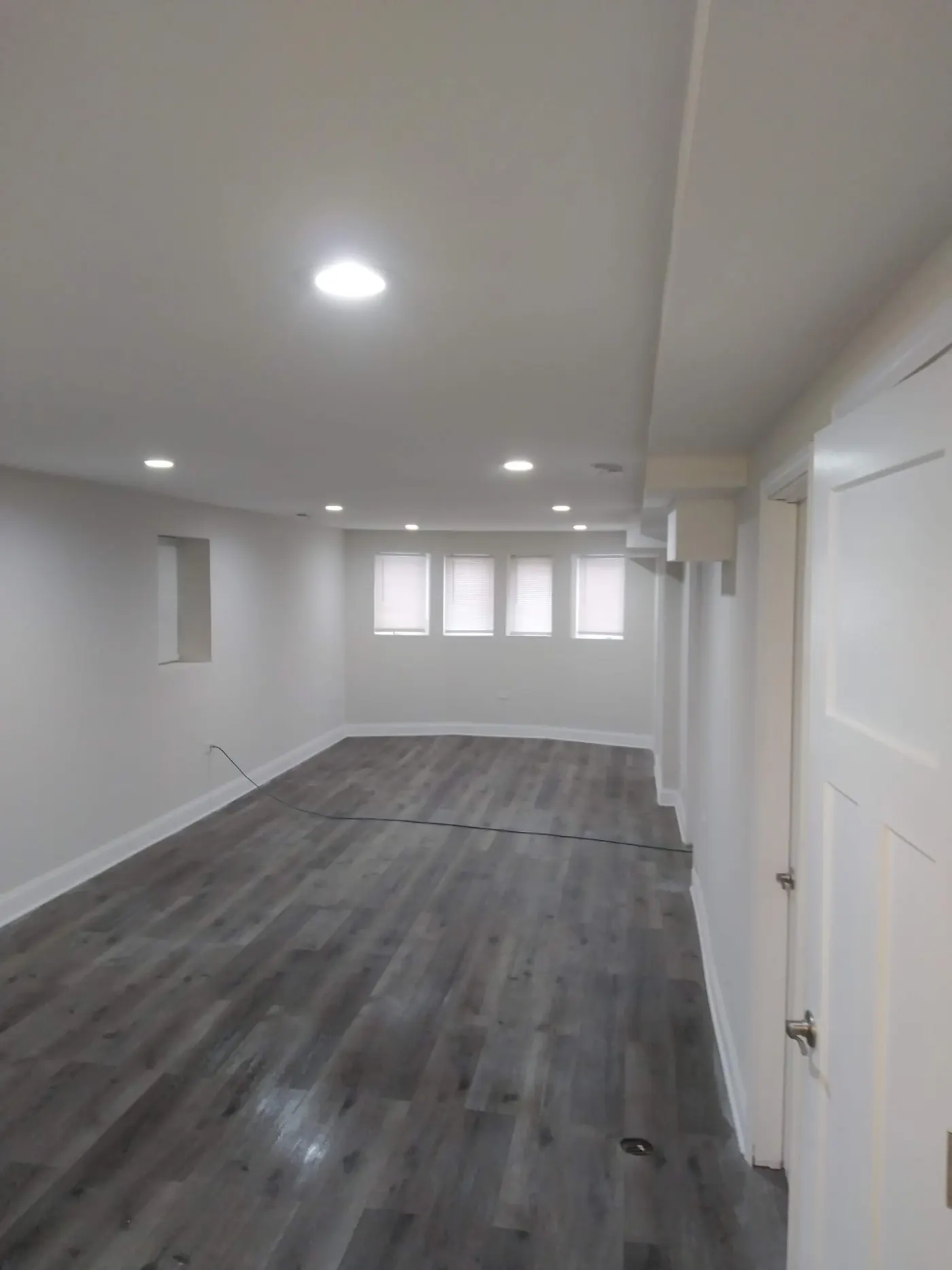 Finished basement room with recessed lighting, new drywall, and dark plank flooring in Bloomingdale