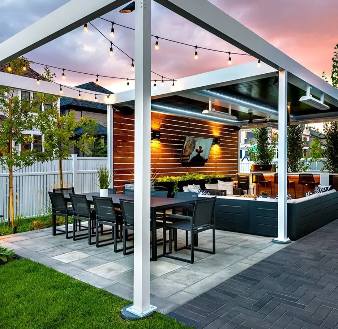 Paver patio under a pergola with an outdoor dining area and string lights