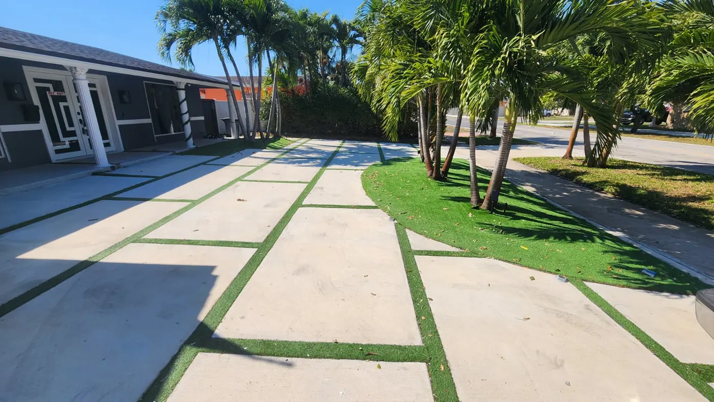 Wide concrete paver walkway with artificial turf inlays leading to a home