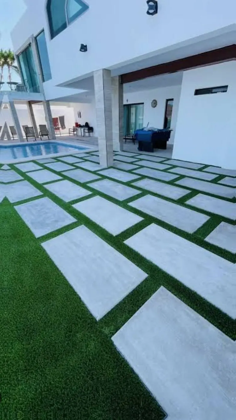 Large concrete pavers set in artificial turf beside a pool deck