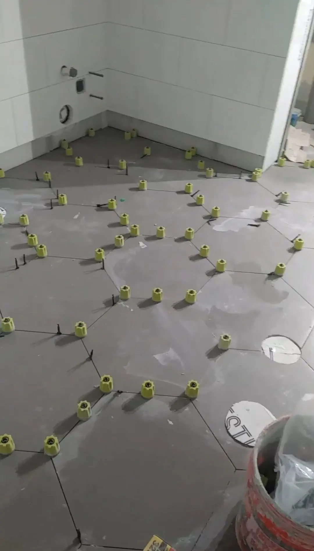 Large-format floor tile being laid with leveling clips