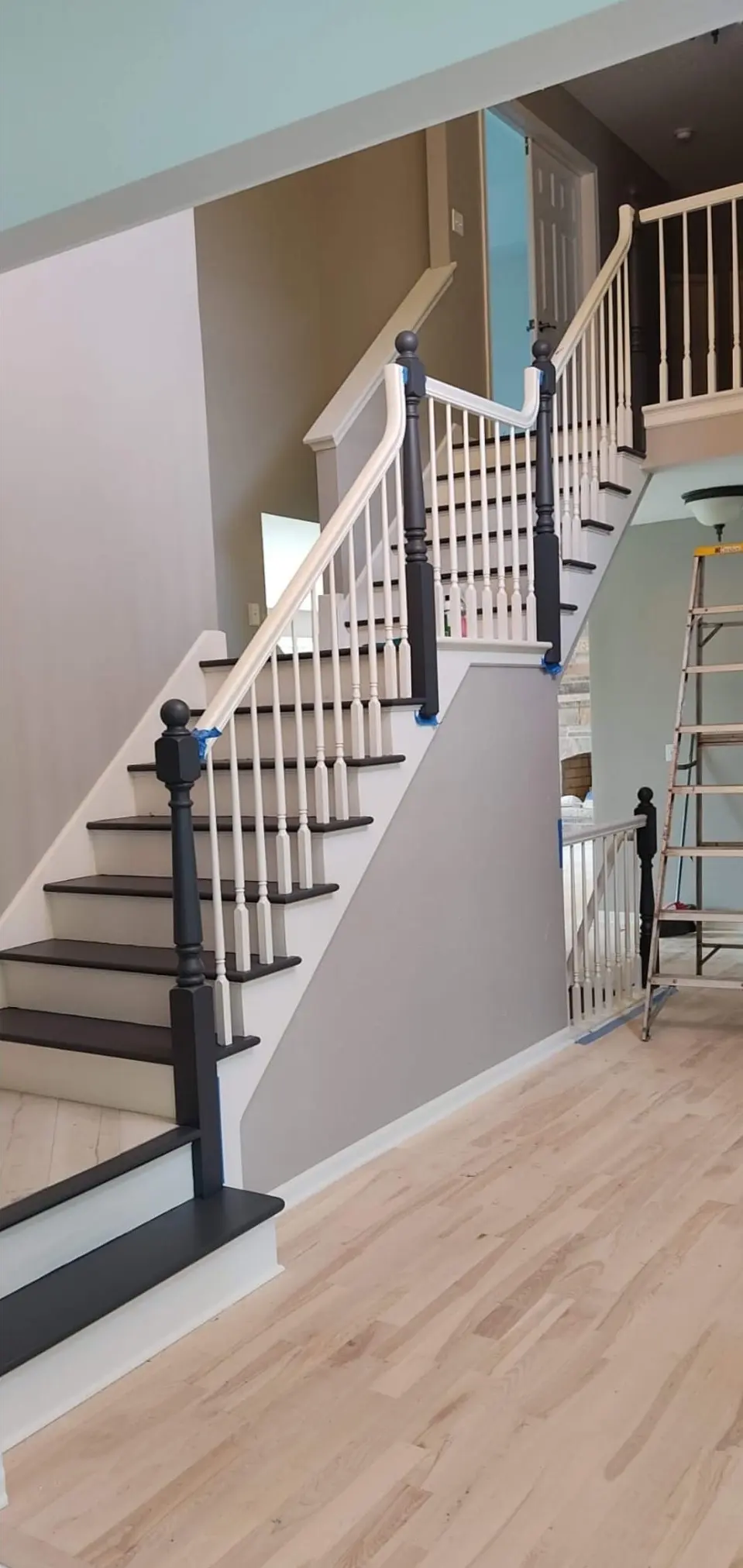 Light hardwood floor at the foot of a staircase with new railing