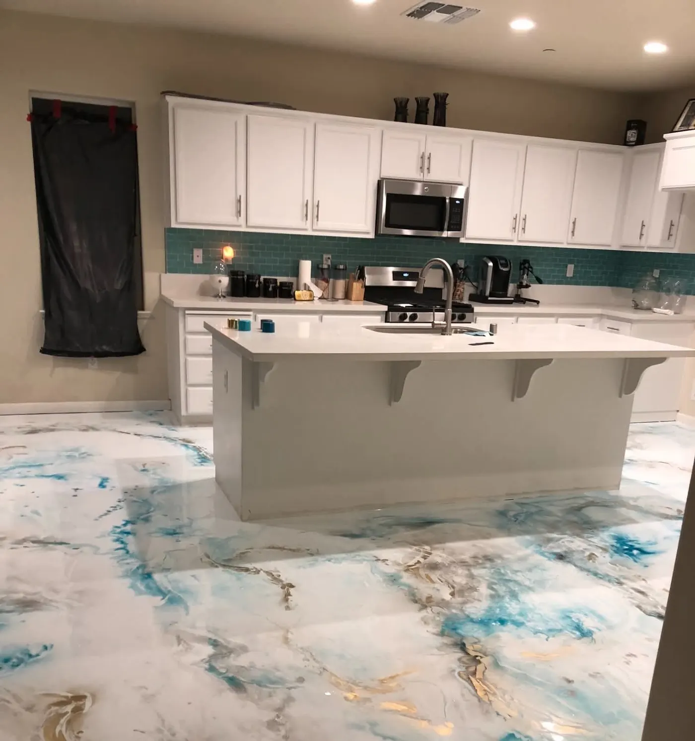 Kitchen remodel with white cabinets, teal glass tile backsplash, island, and marbled epoxy floor in Bloomingdale