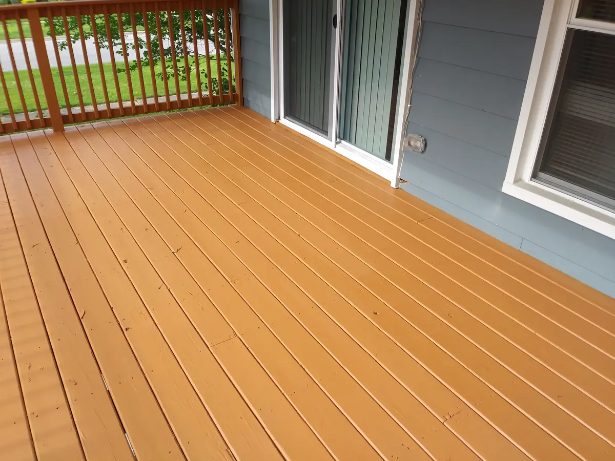 Freshly stained wood deck beside sliding doors and gray siding