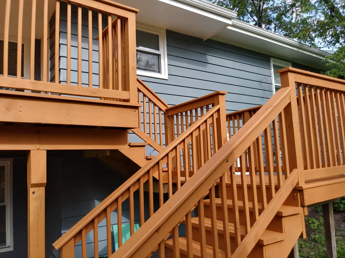 Stained deck stairs and railing on a gray-sided home