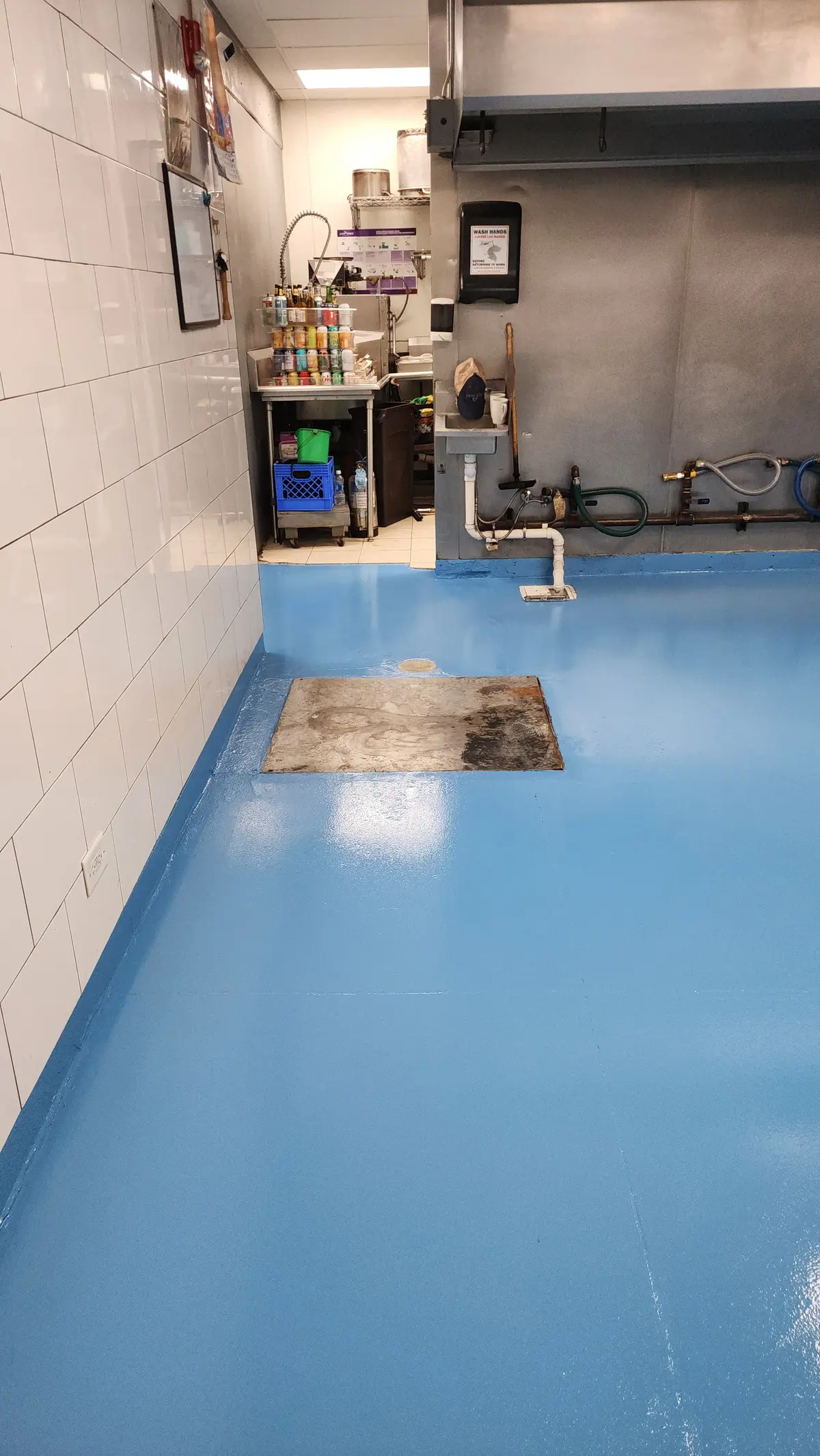 Glossy blue epoxy-coated floor beside white tiled walls
