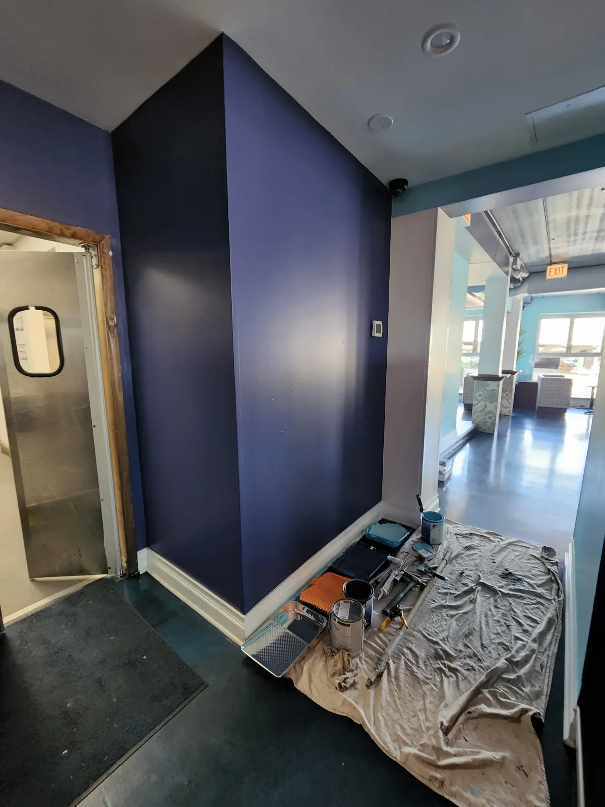 Deep navy accent wall at an entry with drop cloths on the floor